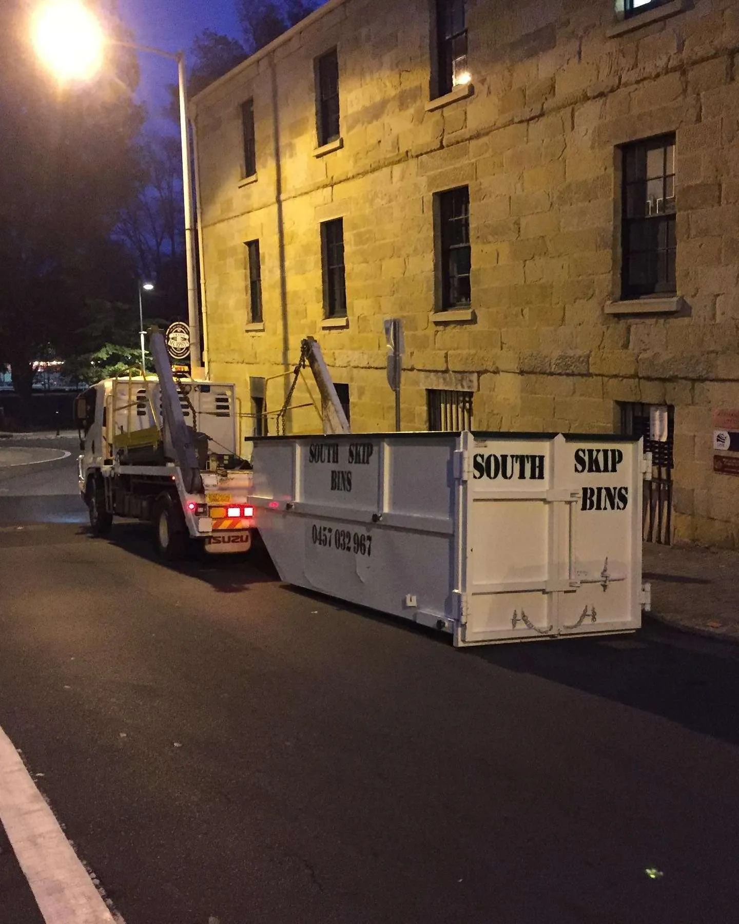 Construction waste skip bin truck delivering a bin at night in Hobart
